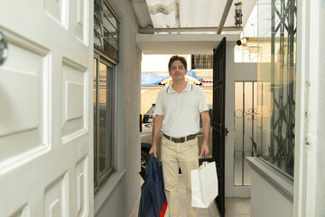 Latino adult man arriving home with gift purchases