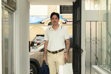 Latino adult man arriving home with gift purchases