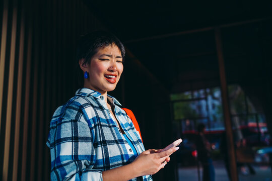Asian woman smiling directly at camera with phone, blending friendliness and digital openness, representing approachability in freelance or mobile-first work culture.