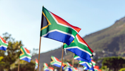 Celebrate South Africa with vibrant flags waving against a clear blue sky and mountain backdrop, inspiring pride, heritage, and national unity