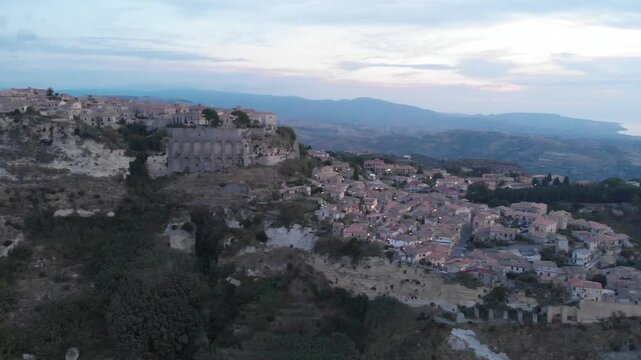 Aerial view: ancient village of Gerace Calabria Italy built on rocky mountain top at sunrise with dramatic cliffs and historic stone houses symbolizing heritage and Mediterranean culture