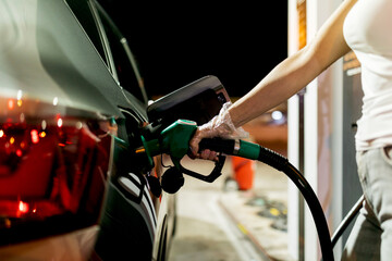 Woman refueling car at night with green nozzle