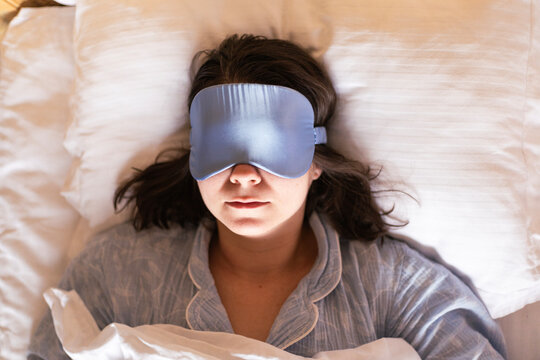Woman resting peacefully with a sleep mask in pajamas