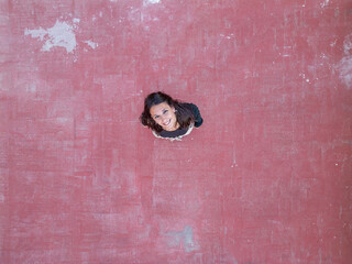 Woman standing on a textured red ground looking up
