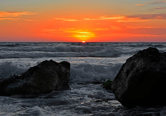 pomarańczowy zachód słońca nad morzem ze wzburzonymi falami, orange sunset over the sea  © kateej