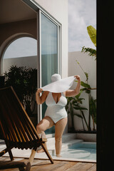 Curvy caucasian female in white swimsuit relaxing by poolside on sunny day