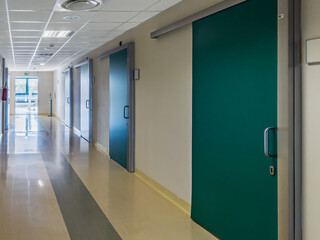 Hospital corridor with green doors leading to the clinics