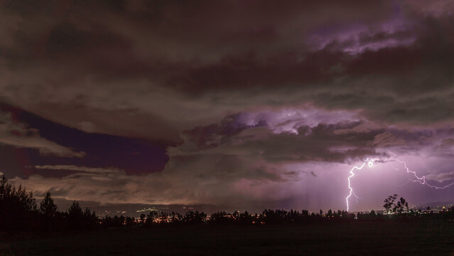 Lightning striking over city under dramatic storm clouds
