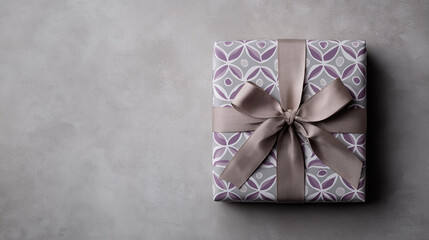 Gift box with satin bow on grey background, top view.