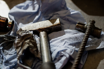 Close-up of metal hammer and mechanical tools placed on workshop surface with used cleaning cloth showing industrial repair environment, maintenance setup, and rugged equipment detail in workspace
