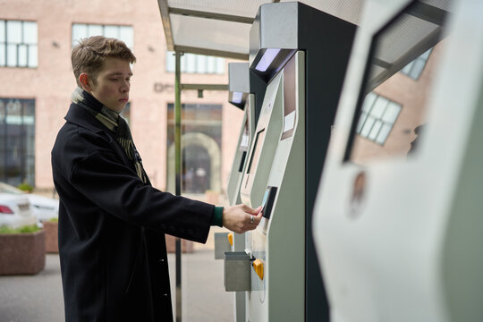 Young man using city kiosk in autumn setting