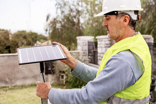 Man holding solar panel outdoors in sunny environment