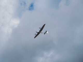 White military reconnaissance UAV in flight showing underside detail against cloudy atmospheric backdrop