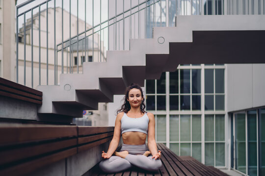Young woman in sportswear practicing lotus pose meditation outdoors. Conceptual stock photo symbolizing balance, mindfulness, wellness, and modern digital-era self-care lifestyle. - Powered by Adobe