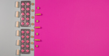 pills, capsules, and tablets arranged diagonally on a pink and gray background. Concept of medicine, healthcare, pharmacy, vitamins, and modern treatment.