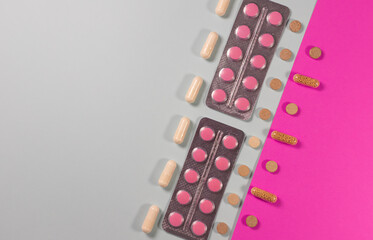 pills, capsules, and tablets arranged diagonally on a pink and gray background. Concept of medicine, healthcare, pharmacy, vitamins, and modern treatment