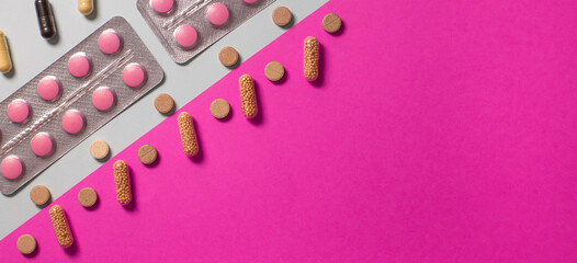pills, capsules, and tablets arranged diagonally on a pink and gray background. Concept of medicine, healthcare, pharmacy, vitamins, and modern treatment.