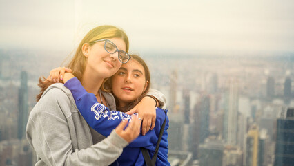 Fototapeta premium Friends embracing with Manhattan cityscape in the background captured from a high-rise building