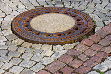 Manhole Cover on Cobblestone Pavement