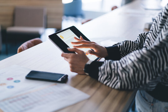 Close-up of woman using digital tablet with stylus, symbolizing interactive data access, mobile-first mindset and smart technology use in remote business routine.