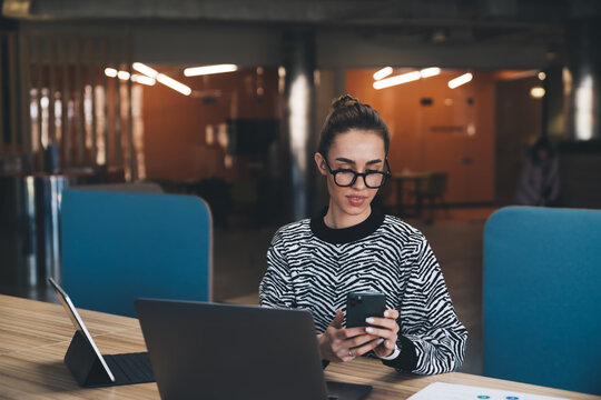 Calm and confident woman in zebra top working on tablet and laptop in contemporary workspace, conveying balance, determination and digital fluency in relaxed business atmosphere.