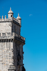 Detail of Belem tower on the river near lisboa, where vasco dagama left for the world. moon on the blue sky background.