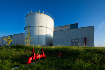 97,000 Gallon Carbon Bolted Steel water Tank, with ow Profile Roof and warehouse behind it