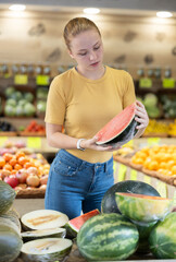 Teenage girl buyer choosing fresh watermelon at vegetable market
