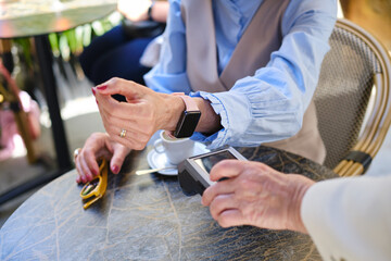 close up shot of hands of Senior woman paying cafe bill using smartwatch contactless technology. unrecognizable person