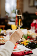 Hand holding champagne glass during festive holiday dinner celebration