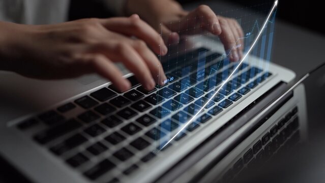Close-up of hands typing on a laptop keyboard with a digital graph overlay, representing technology, data analysis, and modern work environments in action. Copula