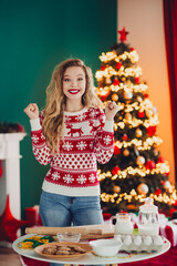 Funny festive baking moment a cheerful blonde woman in a red sweater celebrates Christmas at home...