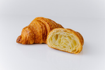 Fresh flaky croissant with airy layers, cut in half, isolated on white background