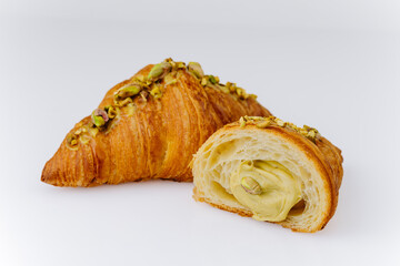 Fresh pistachio croissant with creamy filling on white background, gourmet bakery dessert