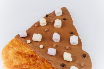 Flaky croissant dipped in milk chocolate with mini marshmallows and crispy pearls, close-up