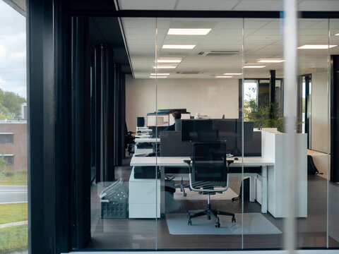Modern open office interior with workstations computers and glass partition viewed through curtained entrance