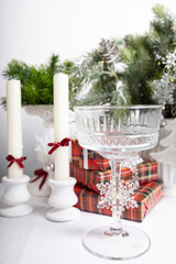 New Year's table setting with white plates, candles and decorative gifts. Red and green accents create a festive atmosphere.