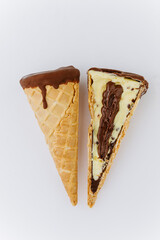 Sliced chocolate and vanilla ice cream cone with creamy filling on white background