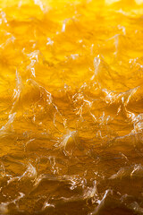 Abstract texture of yellow bearing grease illuminated from below, forming organic shapes, reflections, and patterns resembling the fluid energy of mechanics