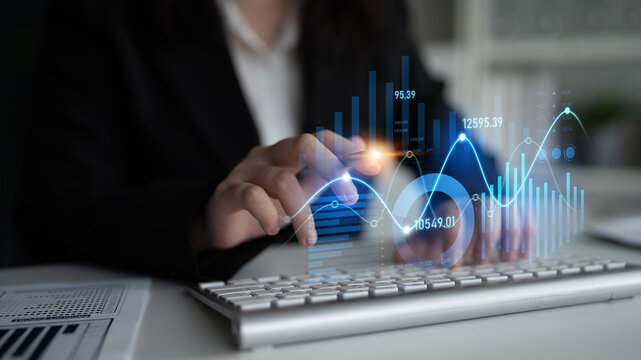 A businesswoman analyzes data using a modern keyboard while interacting with colorful graphs and statistics in a contemporary office space, showcasing data-driven insights. Scalp