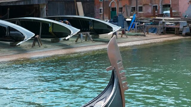 Gondola ferro or prow detail floating on a venice canal. Close-up of a gondola's ferro, the decorative metal piece at the prow, reflecting in the calm canal water of venice, italy