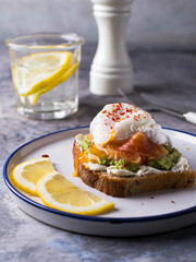 Healthy breakfast with poached egg on toast, avocado and salmon.