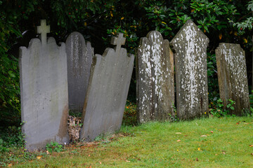 Old graves and headstones in row against hedge