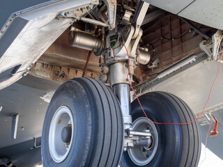 Close-up of main landing gear with retraction mechanism and exposed hydraulic actuators under...