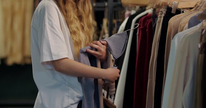Woman checking price tag on gray sweater in store
