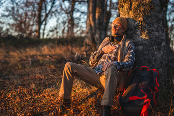 Man hiker relaxing with hand on heart in autumn forest
