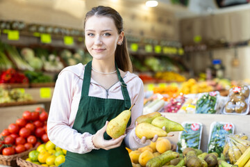 Portrait of girl working in grocery shop, selling ripe pears