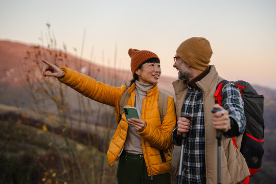 Couple hiking together pointing directions using smart phone navigation
