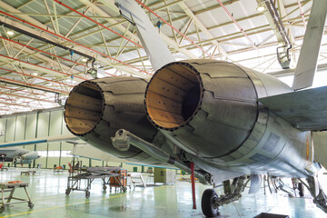 Close view of variable afterburner nozzle petals exhaust area and tailhook on a twin engine multirole fighter jet during maintenance in a hangar