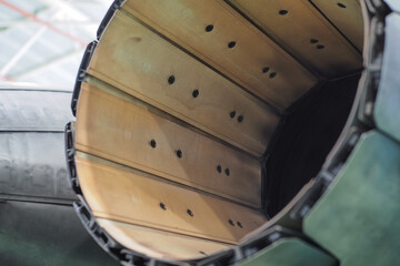 Close view of variable nozzle petal and inner afterburner liner panels with rows of cooling holes on a twin engine multirole fighter jet